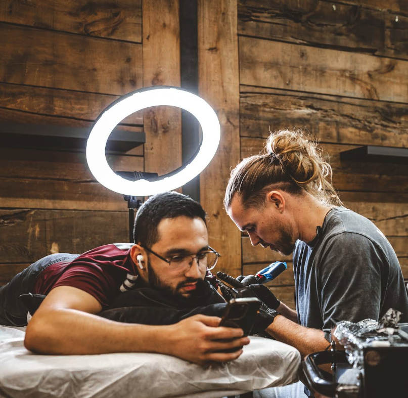 JB tattooing a client under a ring light