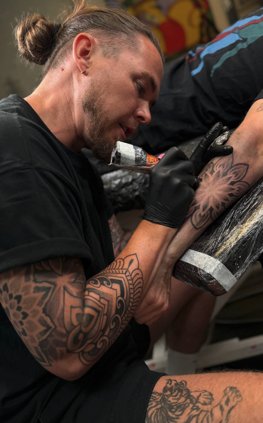 JB tattooing a mandala on a forearm